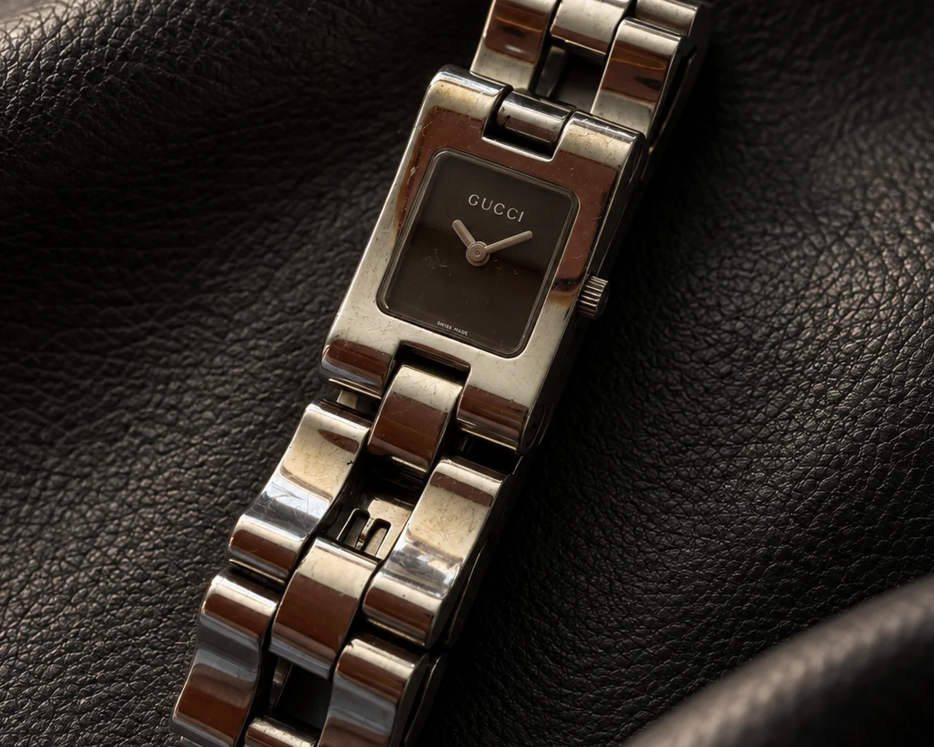 Montre Gucci vintage posée sur un cuir noir texturé