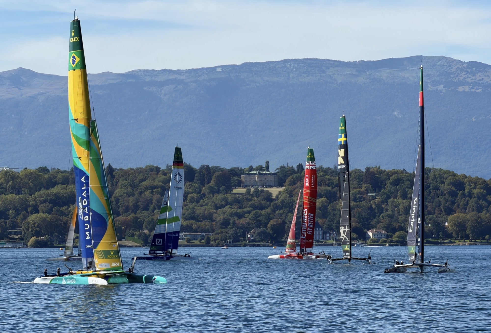 The fleet of F50 catamarans on Lake Geneva with the mountains behind them